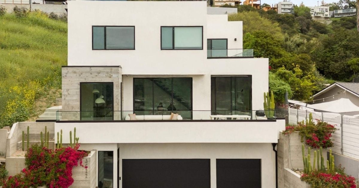 Modern multi-level home with white stucco, black-framed windows, and hillside landscaping in Greater Pasadena, CA.