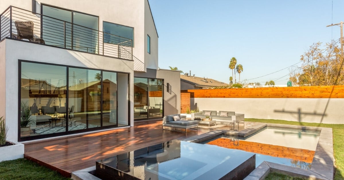 Los Angeles home with sliding glass doors, pool, wood deck, and outdoor lounge chairs.