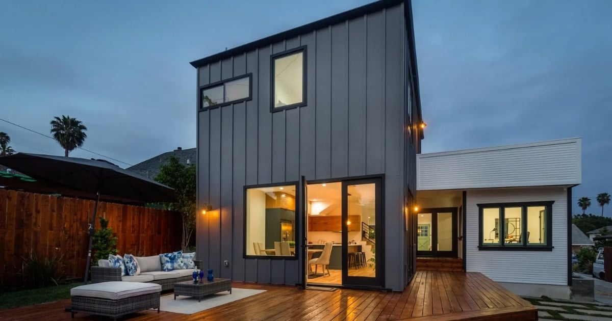 Contemporary home exterior with dark siding, illuminated interiors, and outdoor deck seating in Altadena, CA.